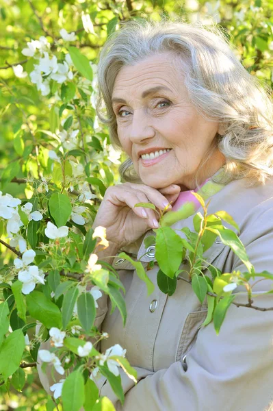 Starší žena poblíž Kvetoucí strom — Stock fotografie