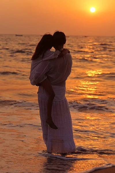 Mother and daughter standing on seashore — Stock Photo, Image