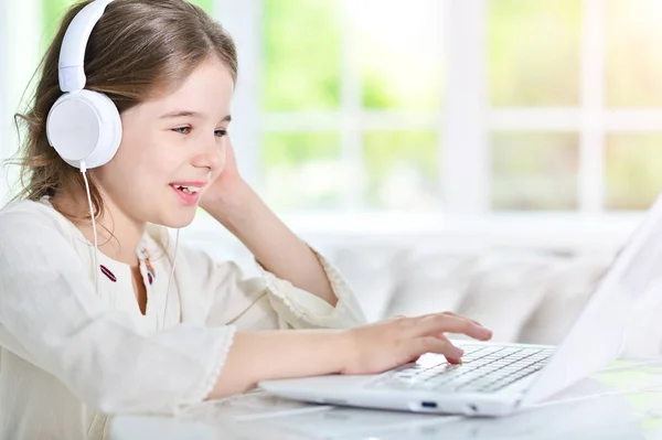 Menina em fones de ouvido usando laptop — Fotografia de Stock