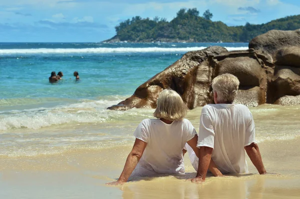 Пара сидящих на тропическом пляже — стоковое фото
