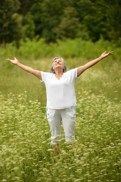 Senior woman standing with open arm — Stock Photo, Image