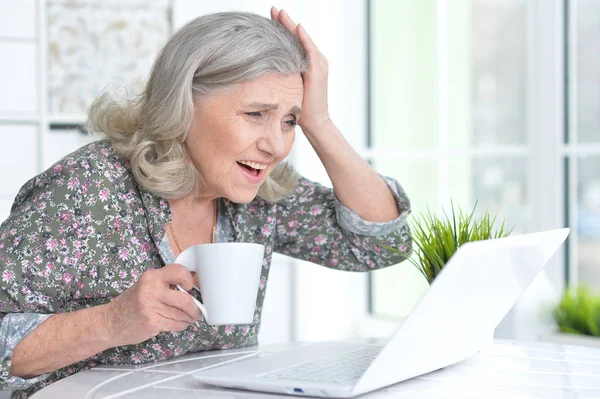 Donna anziana emotiva con computer portatile — Foto Stock