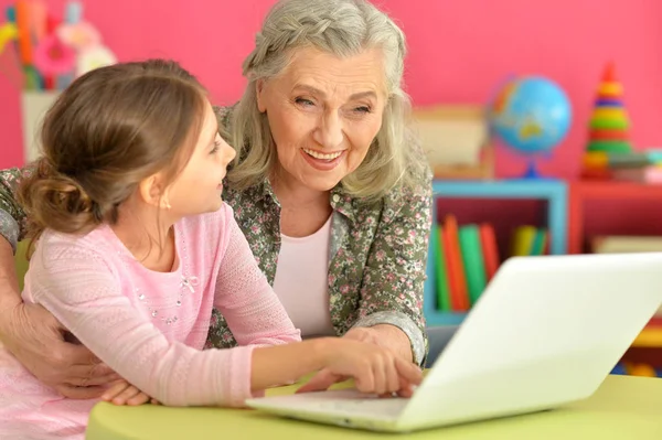 Flicka med mormor använder laptop — Stockfoto