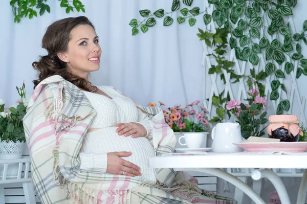 怀孕的女人坐在桌旁 — 图库照片