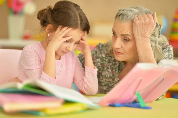 Grandmother and granddaughter doing homework — Stock Photo, Image