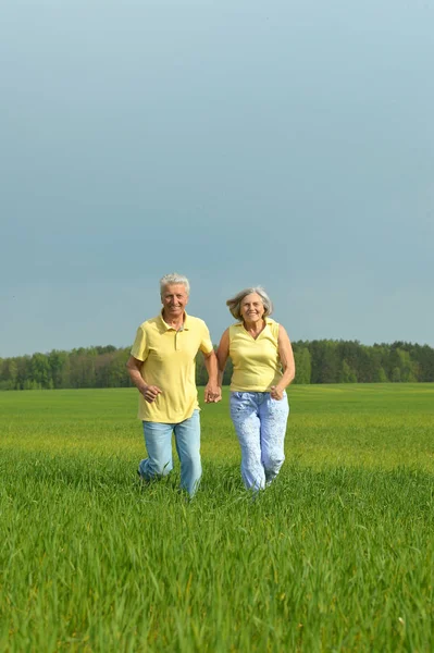 Senior couple running in field — Stock Photo, Image