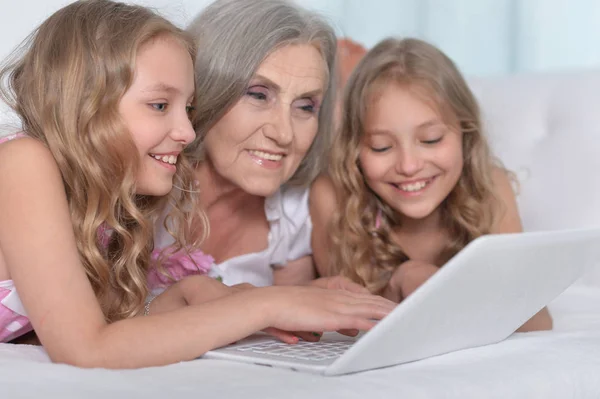 Granny with granddaughters using laptop — Stock Photo, Image