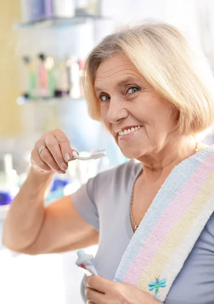 Mujer mayor cepillándose los dientes — Foto de Stock