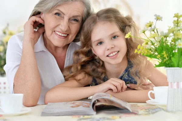 Grootmoeder met meisje lezing magazine — Stockfoto