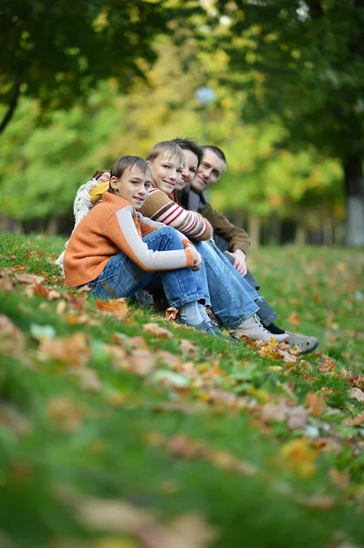 Glücklich lächelnde Familie sitzt auf Blättern — Stockfoto