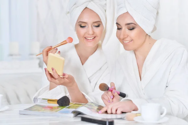 Mujeres con albornoces blancos con revista — Foto de Stock