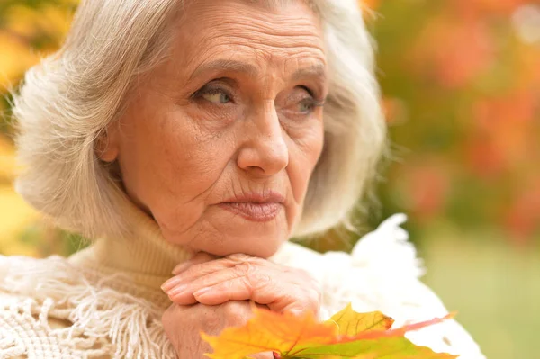 Sad woman holding autumn leaves — Stock Photo, Image