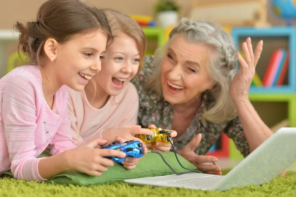 Großmutter und Enkelinnen spielen am Laptop — Stockfoto