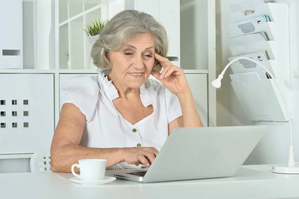 Mujer sentada a la mesa con portátil — Foto de Stock