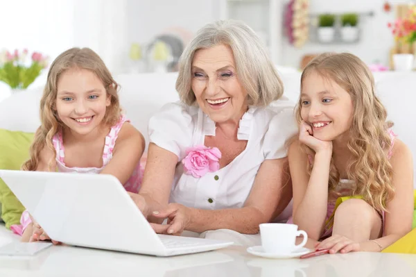 Granny with granddaughters using laptop — Stock Photo, Image