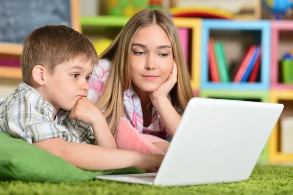 Bry sig och syster med laptop — Stockfoto