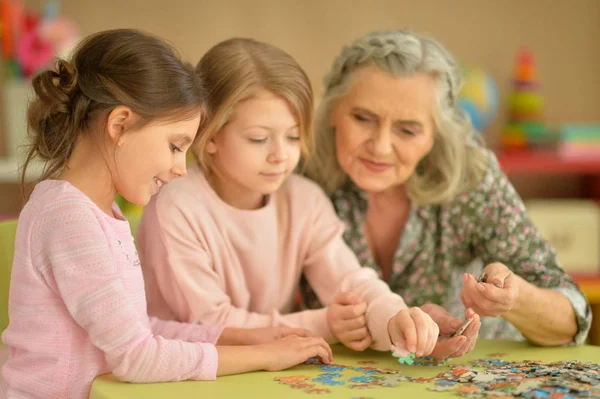 Dziewczynki z babcią zbierać puzzle — Zdjęcie stockowe