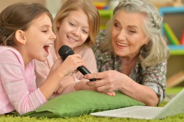 Senior woman with granddaughters singing karaoke — Stock Photo, Image