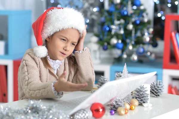 Petite fille dans Santa chapeau avec ordinateur portable — Photo