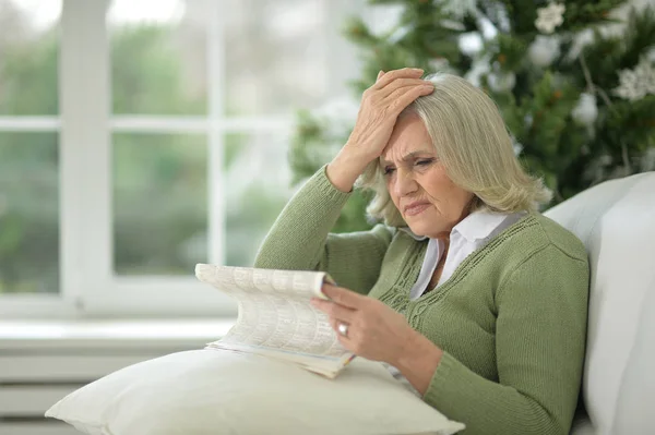 Upset senior woman with newspaper — Stock Photo, Image