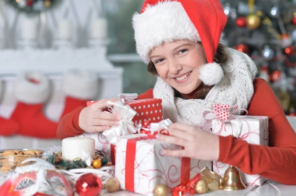 Fille en chapeau de Père Noël avec des cadeaux — Photo