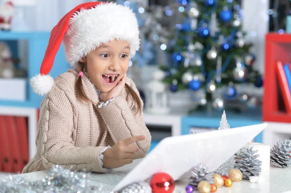 Bambina in cappello Babbo Natale con computer portatile — Foto Stock