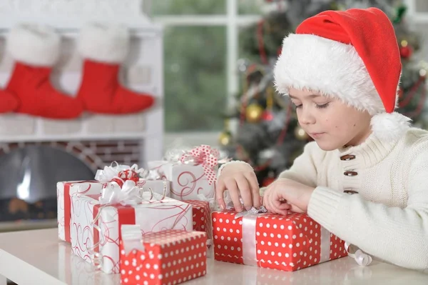 Garçon en chapeau de Père Noël avec des cadeaux — Photo