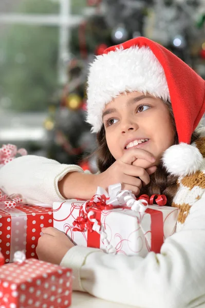 Fille en chapeau de Père Noël avec des cadeaux — Photo