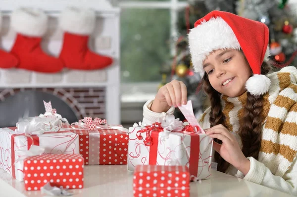 Menina em chapéu de Santa com presentes — Fotografia de Stock