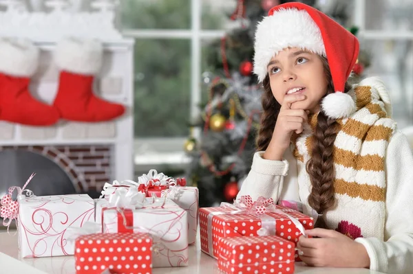 Fille en chapeau de Père Noël avec des cadeaux — Photo