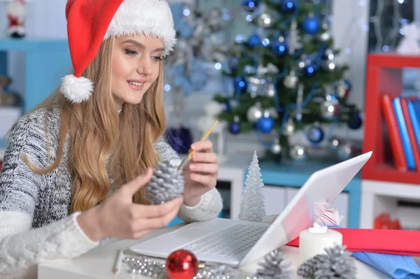 Frau mit Weihnachtsmütze macht Dekoration — Stockfoto