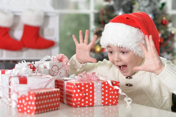 Jongen in kerstmuts met geschenken — Stockfoto