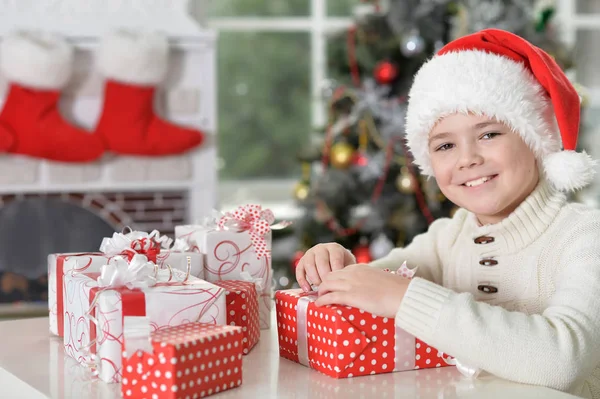 Menino em chapéu de Santa com presentes — Fotografia de Stock
