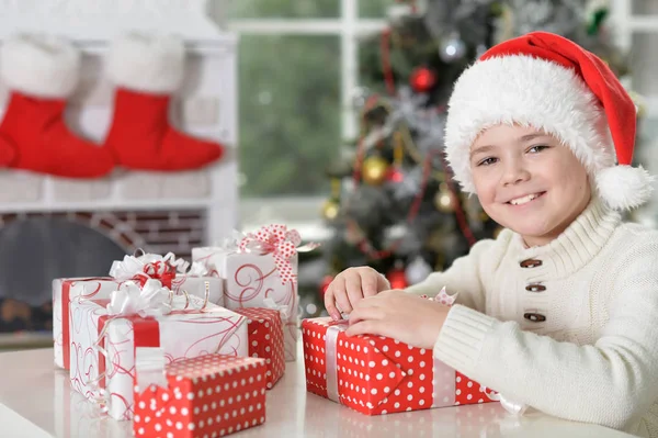 Junge mit Weihnachtsmütze und Geschenken — Stockfoto