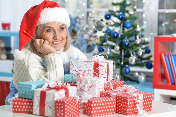 Vrouw in kerstmuts met presenteert — Stockfoto