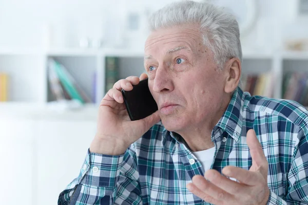 Старший мужчина с телефоном дома — стоковое фото