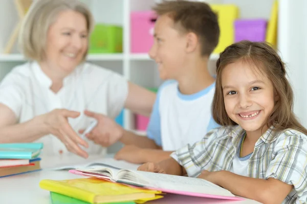 Oma mit Enkeln bei den Hausaufgaben — Stockfoto