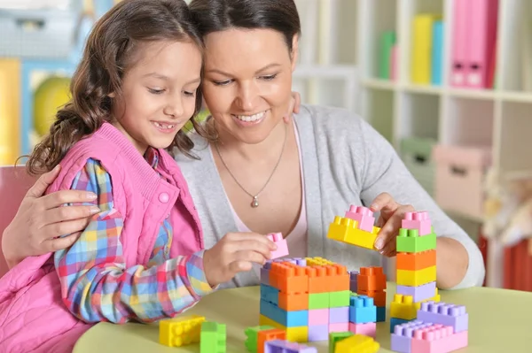 巻き毛の小さな女の子と彼女の母親は カラフルなプラスチック製のブロックで遊んで — ストック写真