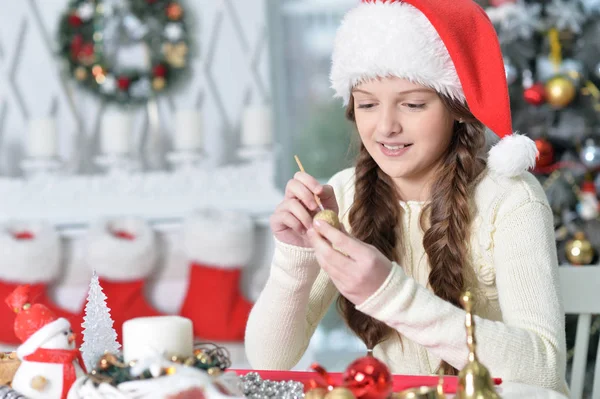 快乐的女孩在圣诞老人的画像准备圣诞节坐在桌子上 — 图库照片