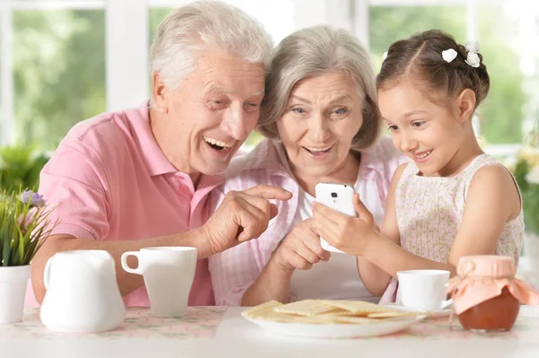 Avós Sorridentes Com Neta Usando Smartphone — Fotografia de Stock