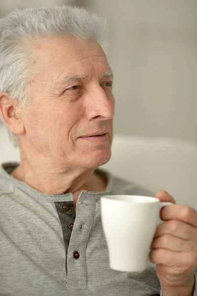 年配の男性がコーヒーを飲みながら笑みを浮かべてください — ストック写真