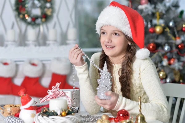 Masada Oturan Noel Için Hazırlanıyor Santa Şapkalı Mutlu Kız Portresi — Stok fotoğraf