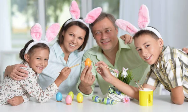 Glückliche Vierköpfige Familie Trägt Hasenohren Und Bemalt Ostereier Hause — Stockfoto