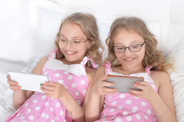 Dwie siostry bliźniaczki za pomocą smartfonów — Zdjęcie stockowe