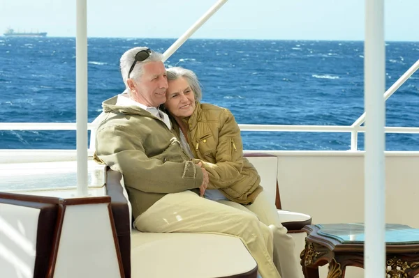 Smiling elderly couple resting on yacht in sea