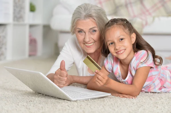 portrait of happy  grandmother and granddaughter using laptop, online shopping concept