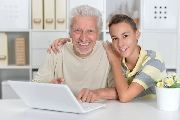ノートパソコンを持った少年と祖父の肖像画です — ストック写真
