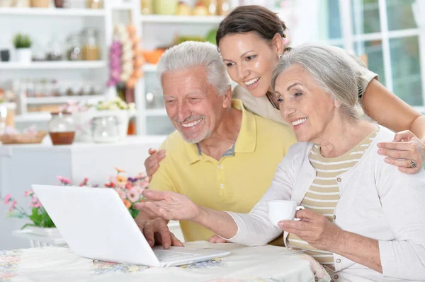 快乐的老年夫妇与成年女儿使用笔记本电脑在家里 — 图库照片