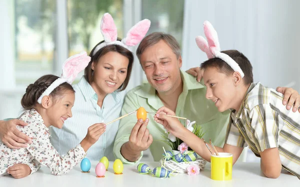 Glückliche Vierköpfige Familie Trägt Hasenohren Und Bemalt Ostereier Hause — Stockfoto