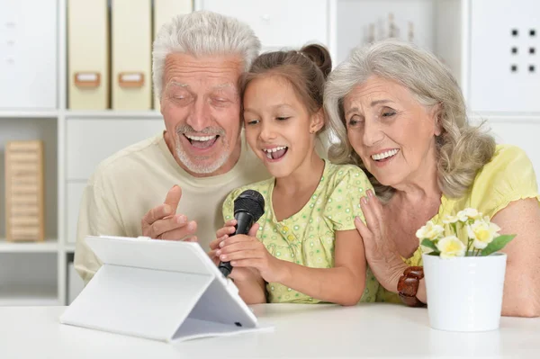 彼女の孫娘はタブレットを自宅でカラオケを歌うと祖父母 — ストック写真